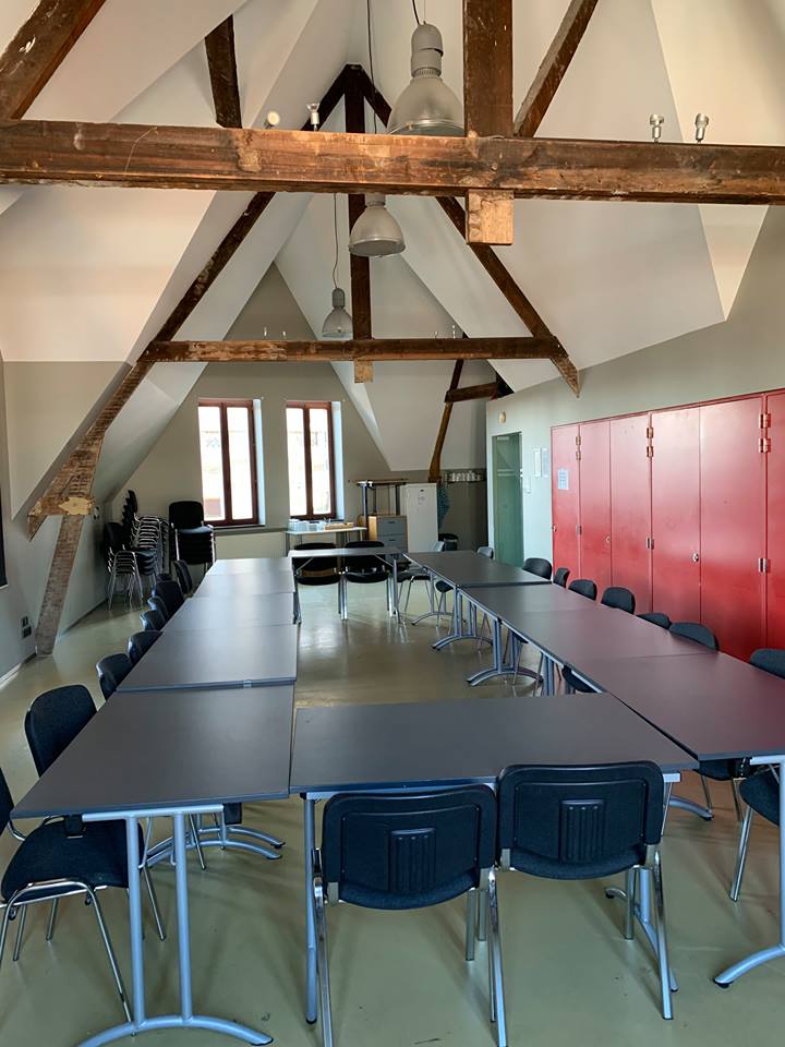 Zaal met 12 tafels en koelkast onder de nok van het dak
